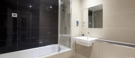 A modern bathroom with a glass-enclosed shower, a white sink, and a toilet.