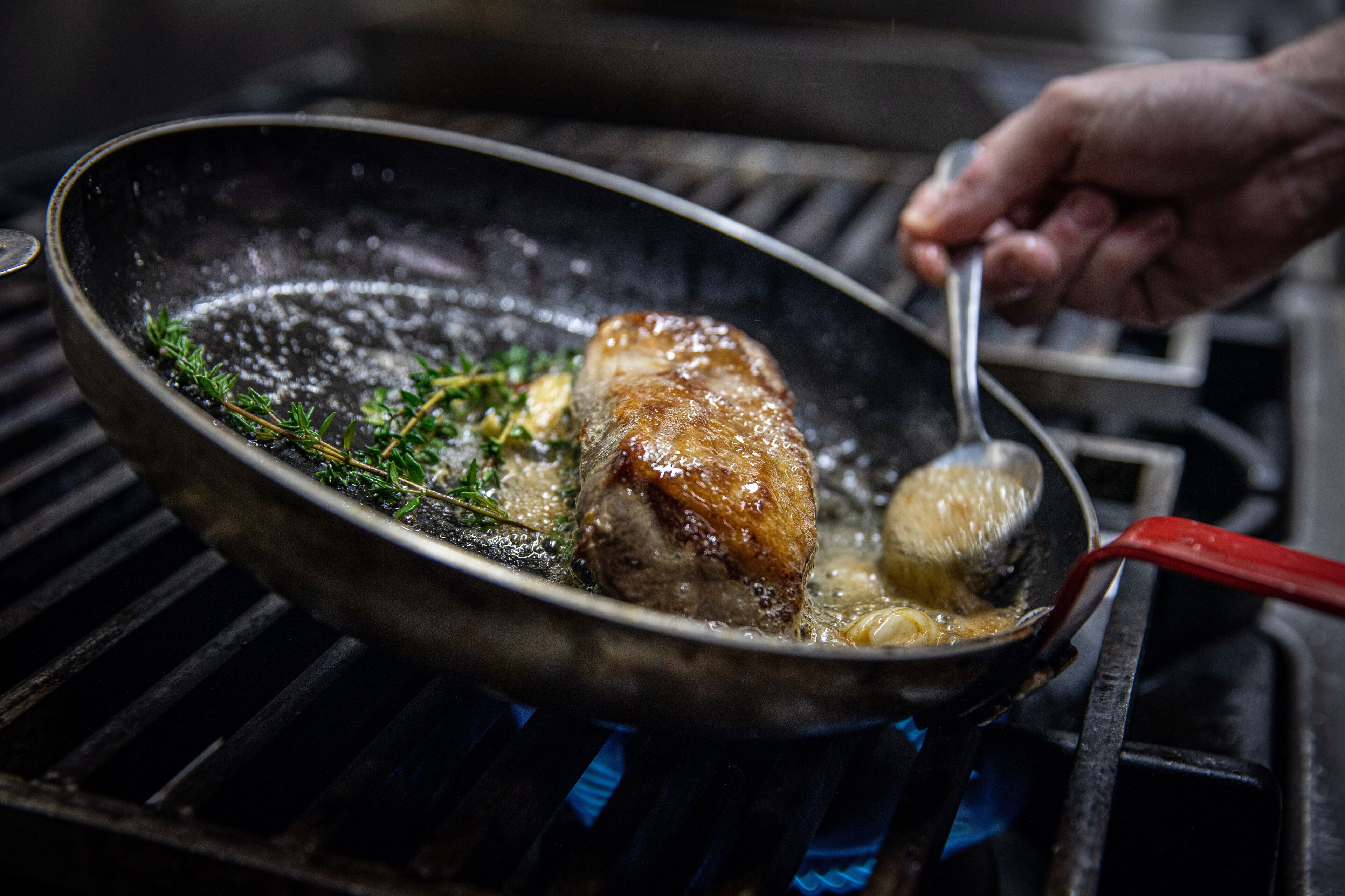 Une poêle sur laquelle on fait cuire un morceau de viande sur un gril.
