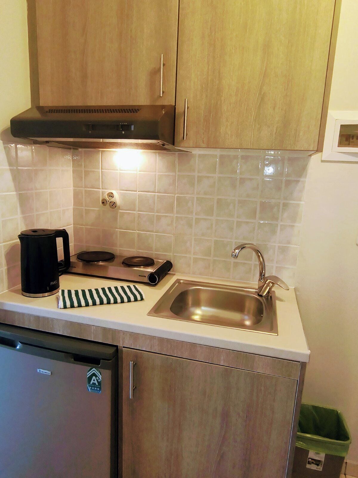 A compact kitchen with a stove, sink, and a small refrigerator.