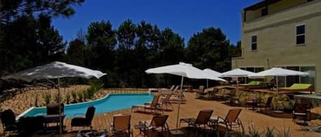 Una piscina al aire libre, sillones reclinables de piscina