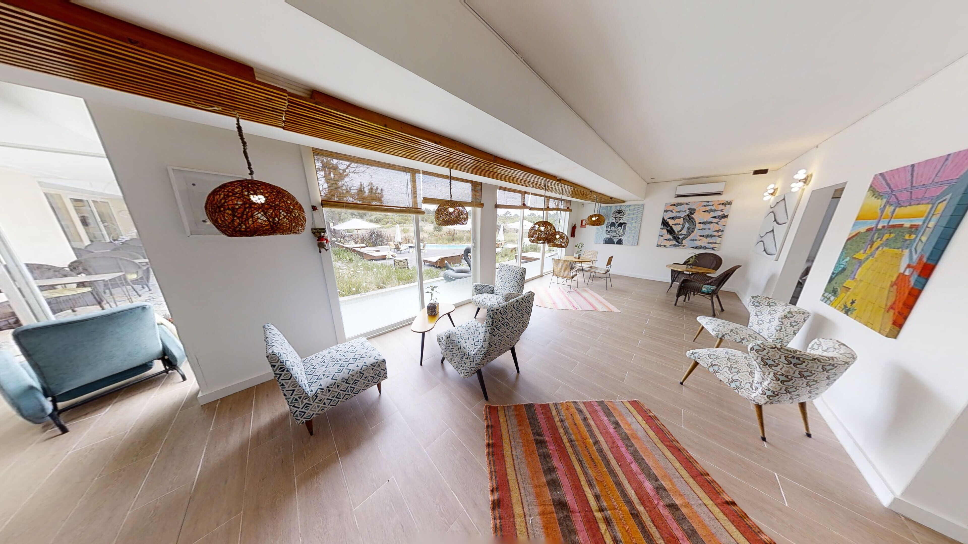 A spacious living area with modern furniture, large windows, and artwork on the walls.