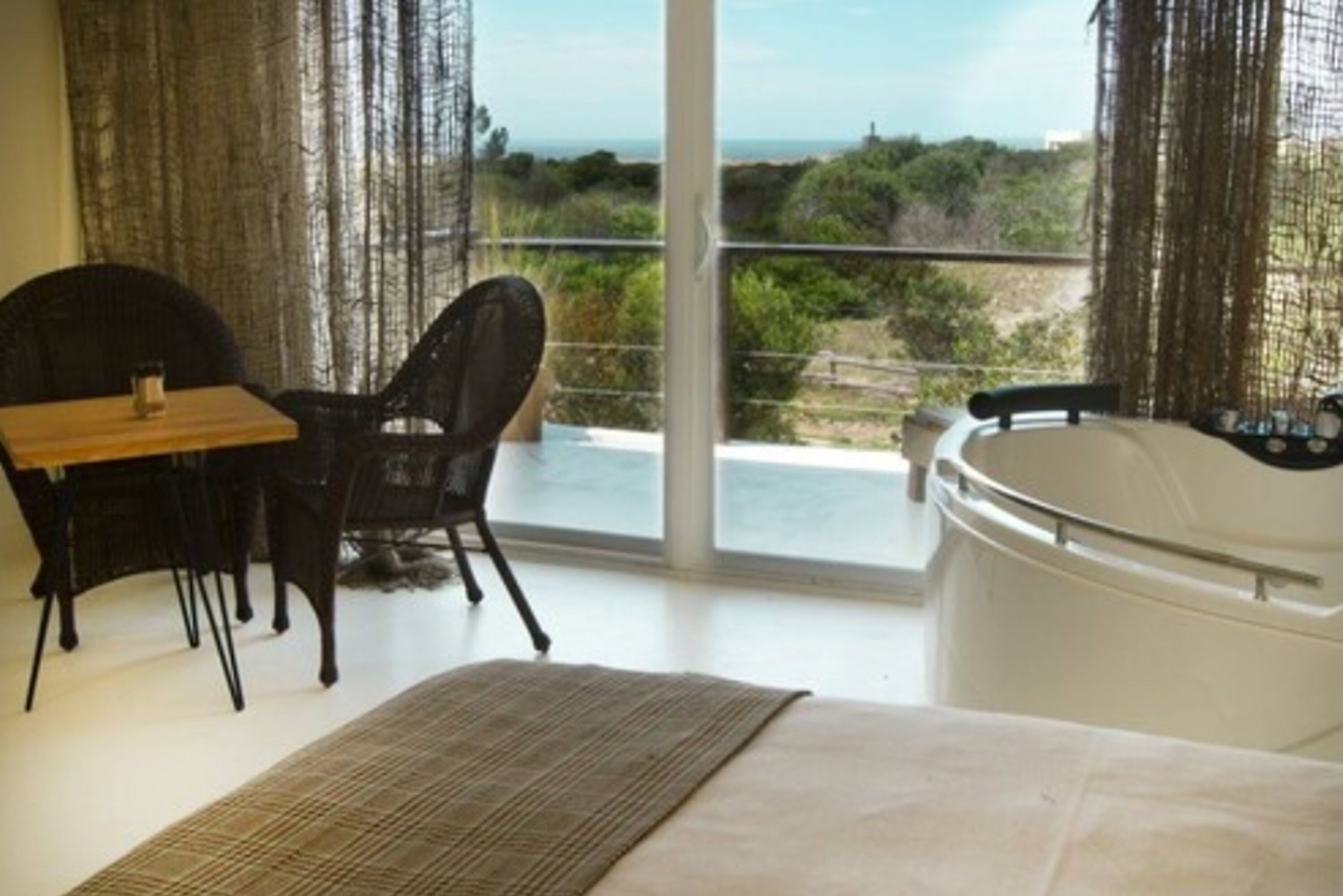 Una habitación con cama, mesa, silla y bañera de hidromasaje.