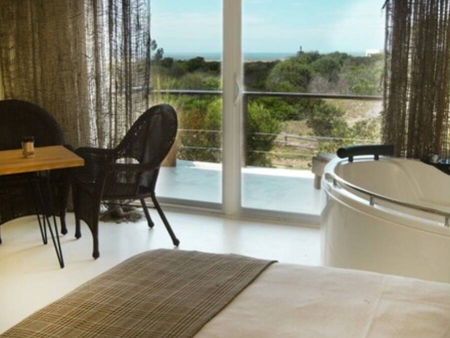 Una habitación con cama, mesa, silla y bañera de hidromasaje.
