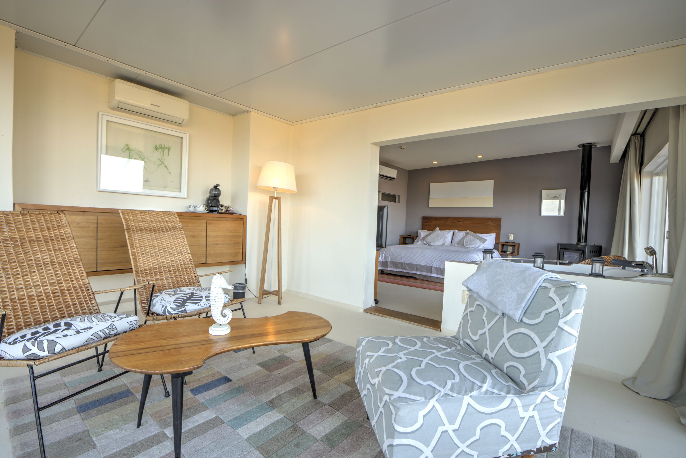 A hotel room with a bed, a desk, two chairs, a lamp, and a framed picture on the wall.