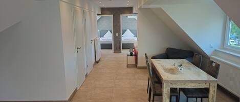 Un interior moderno con zona de comedor, cocina y dormitorio, visibles a través de una puerta abierta.