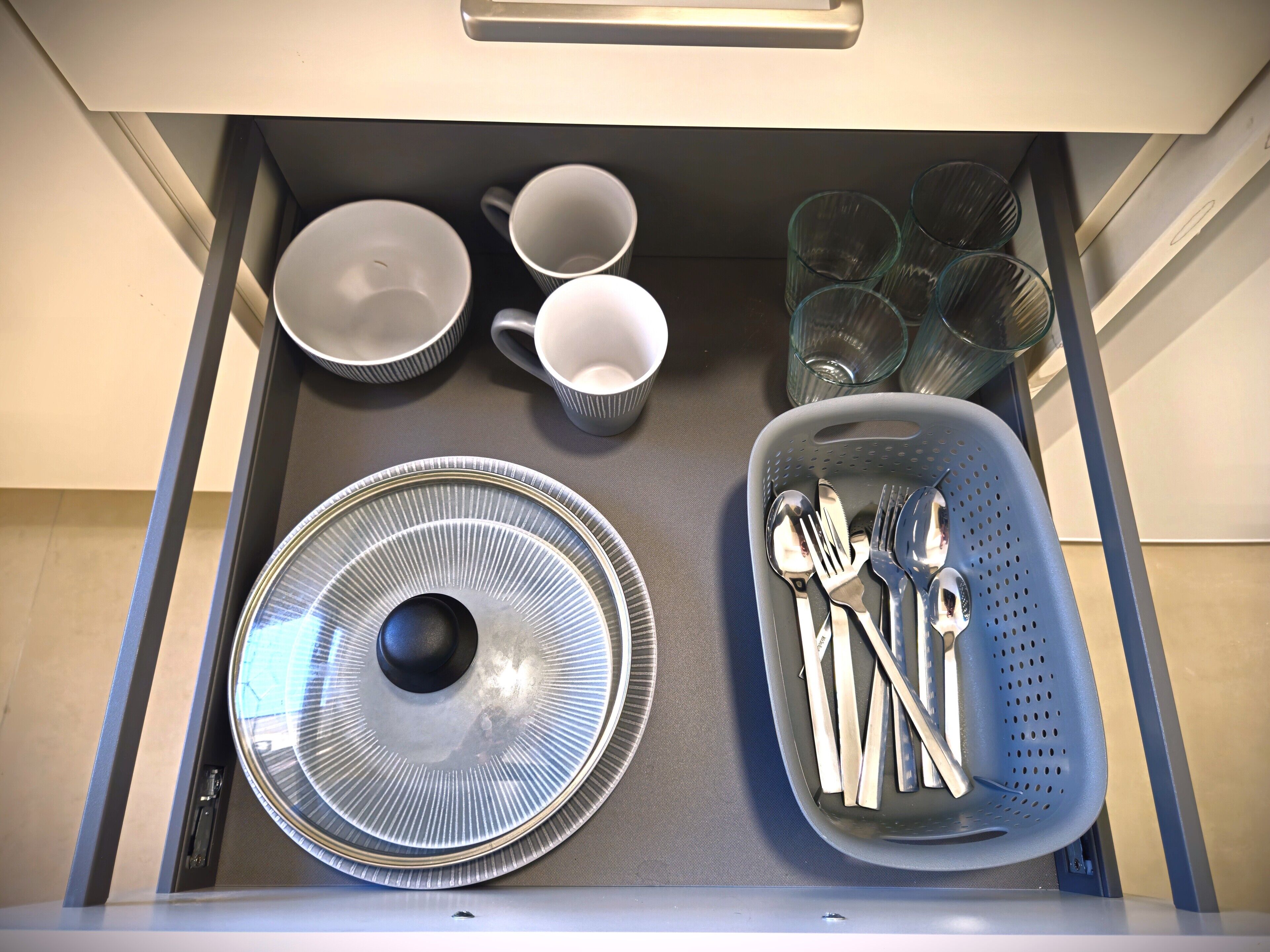 A drawer with plates, bowls, cups, and cutlery.