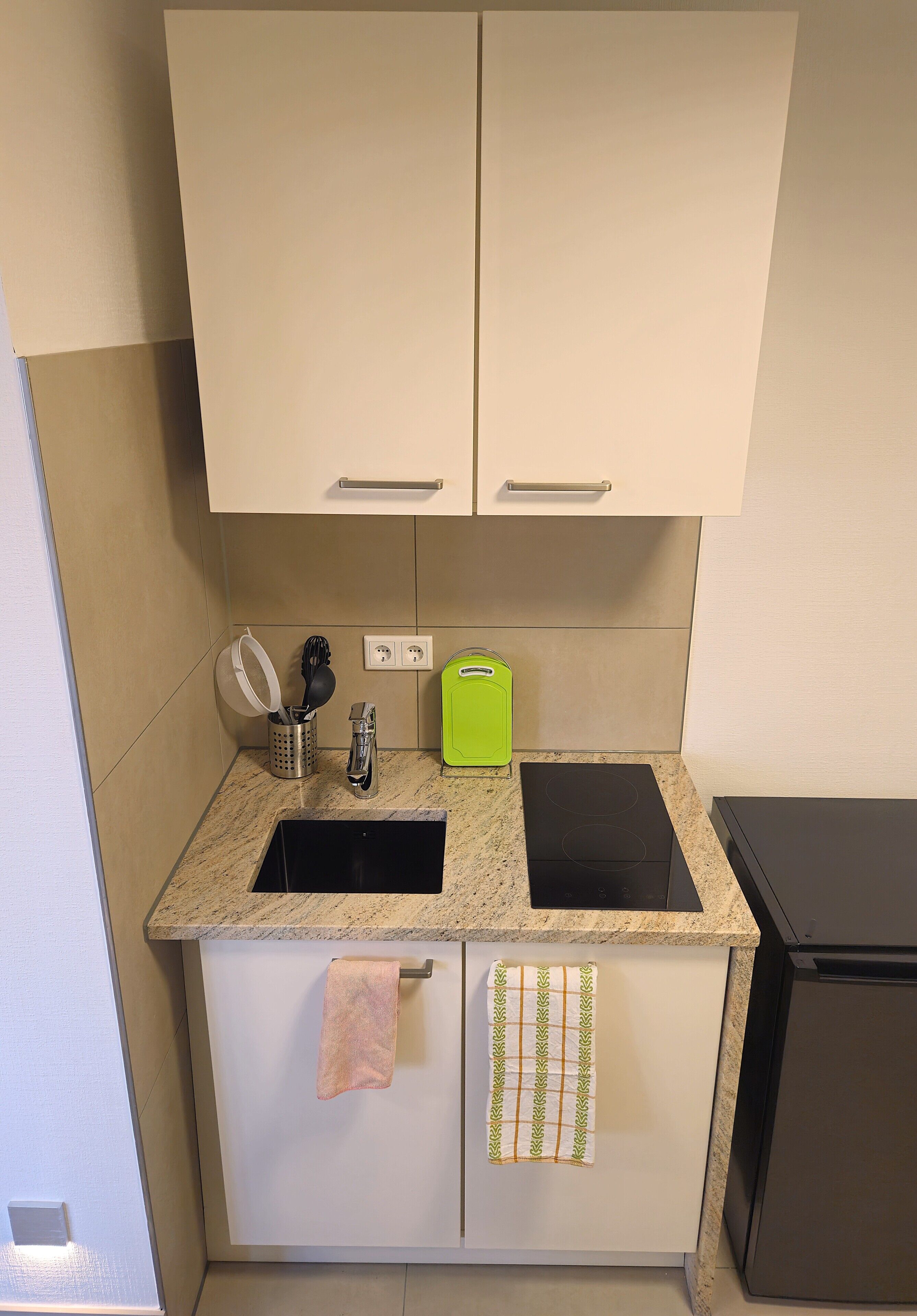 A kitchen with a double sink, a stove, and a small trash bin.
