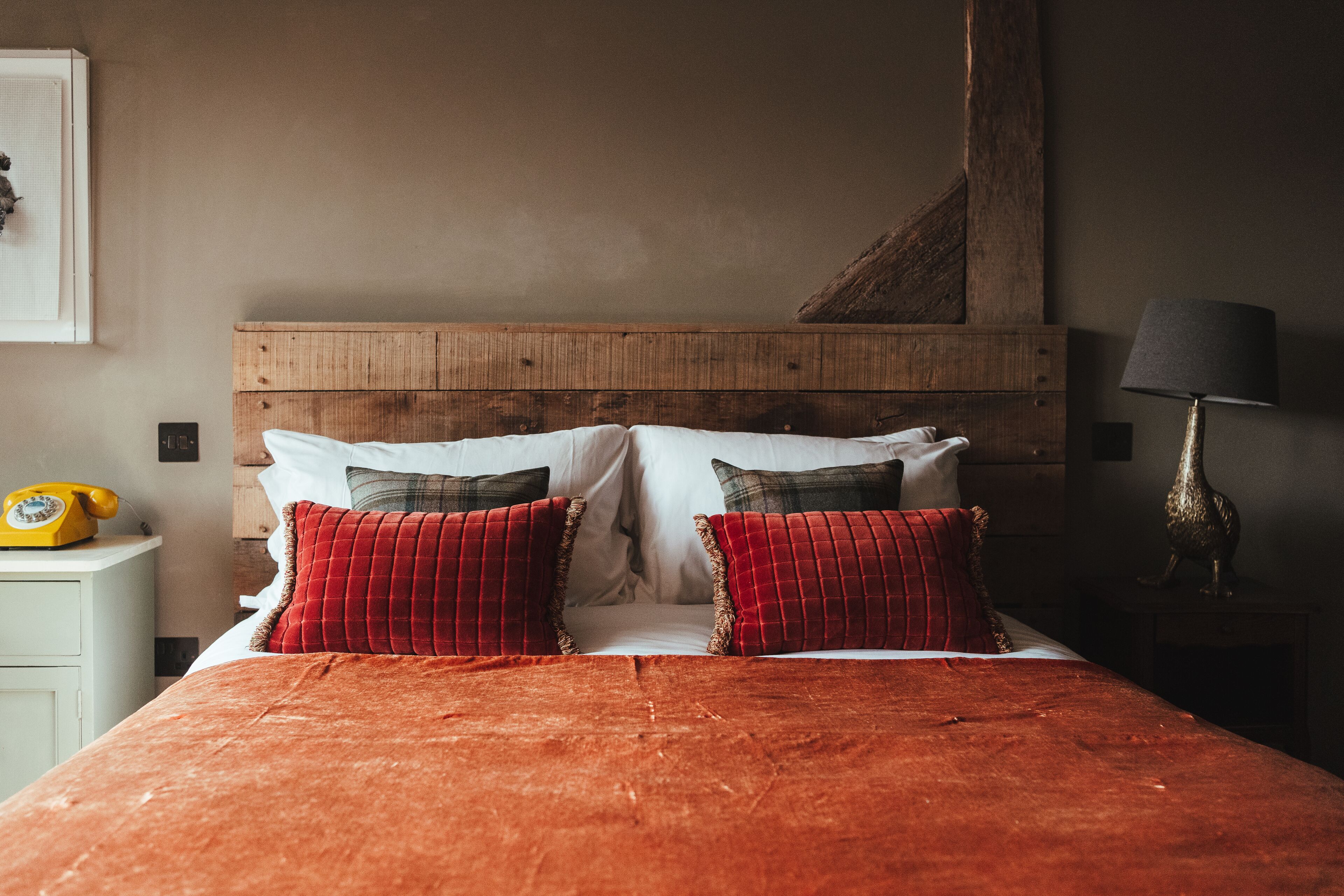 A bed with a wooden headboard, two red pillows, and a red blanket.