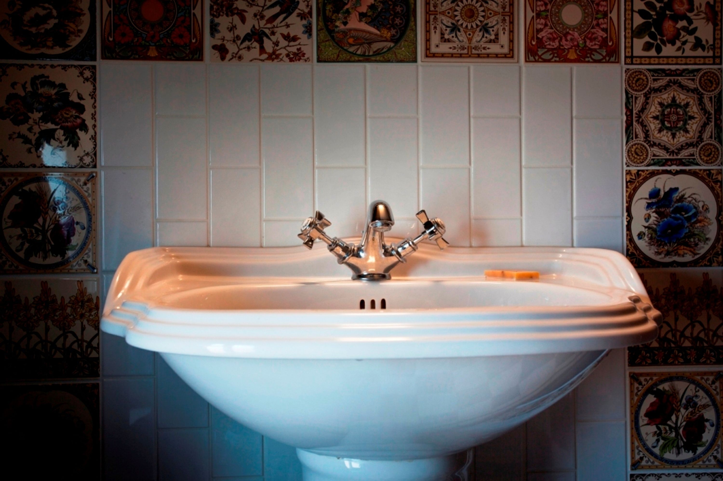 Een wit badkamermeubel met een wasbak en een enkele kraan, omringd door decoratieve tegels.