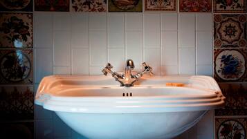 A white bathroom sink with a single faucet, surrounded by decorative tiles.