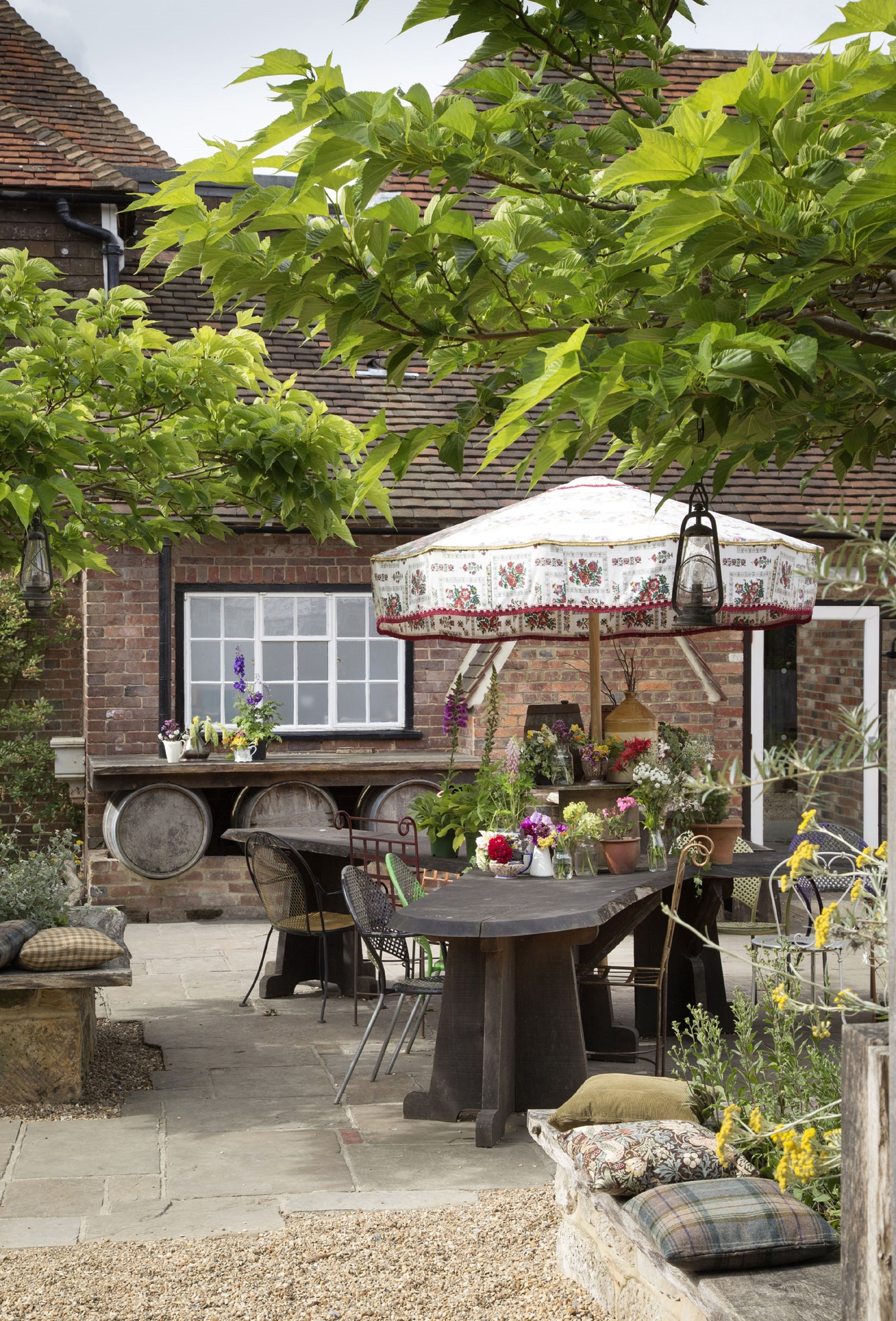 A rustic outdoor seating area with a table, chairs, and a hanging lantern.