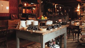A rustic café with a wooden table displaying various breakfast items and a bookshelf in the background. - The Bell in Ticehurst (Wadhurst)