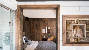 A bedroom with a wooden wardrobe, a bed with a grey blanket, a bedside table with a lamp, and a framed artwork on the wall. - The Bell in Ticehurst (Wadhurst)