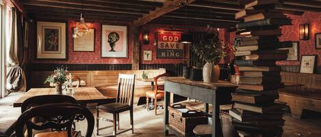 A cozy, rustic interior with wooden furniture, a bookshelf, and framed pictures on the walls.
