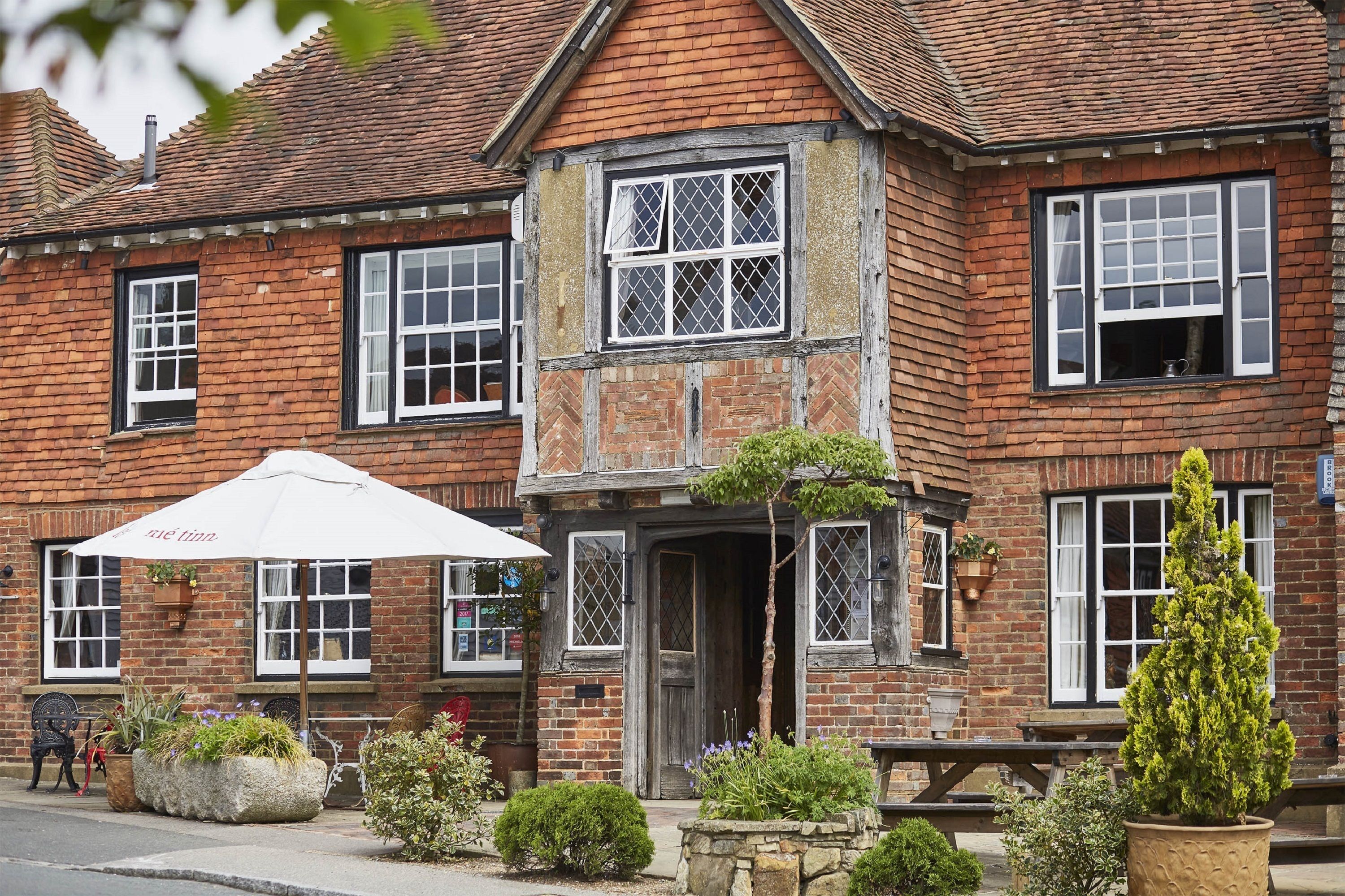 A traditional brick building with a stone entrance, large windows, and outdoor seating.