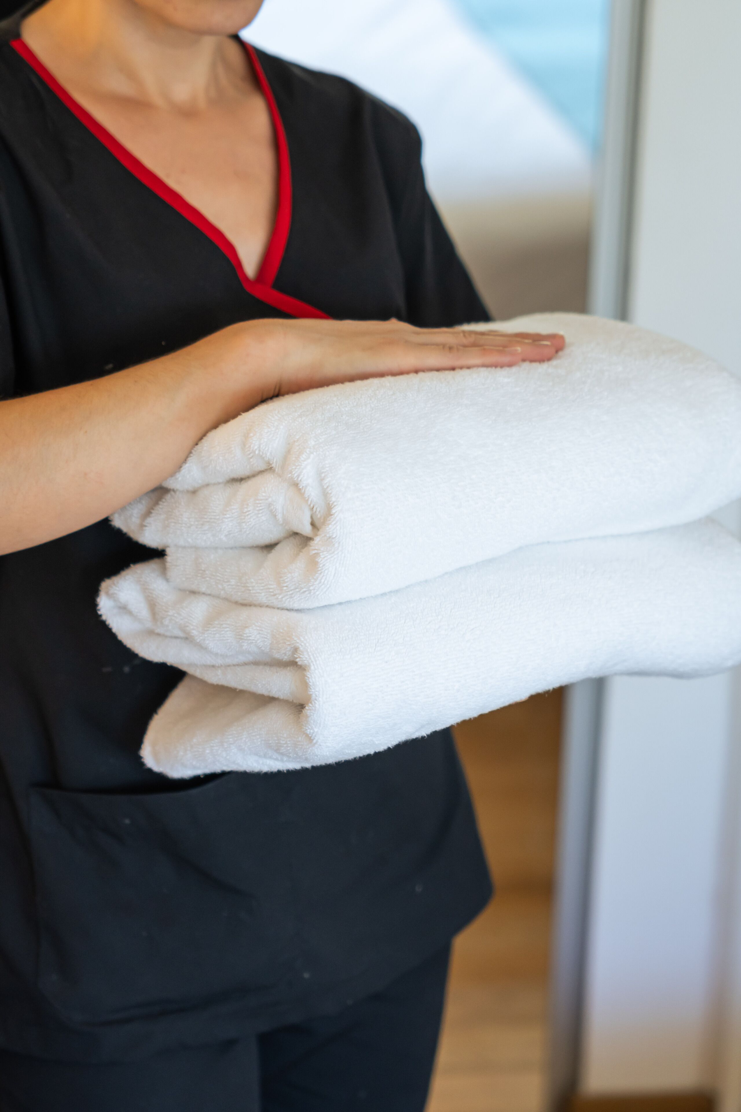 A person holding a stack of white towels.