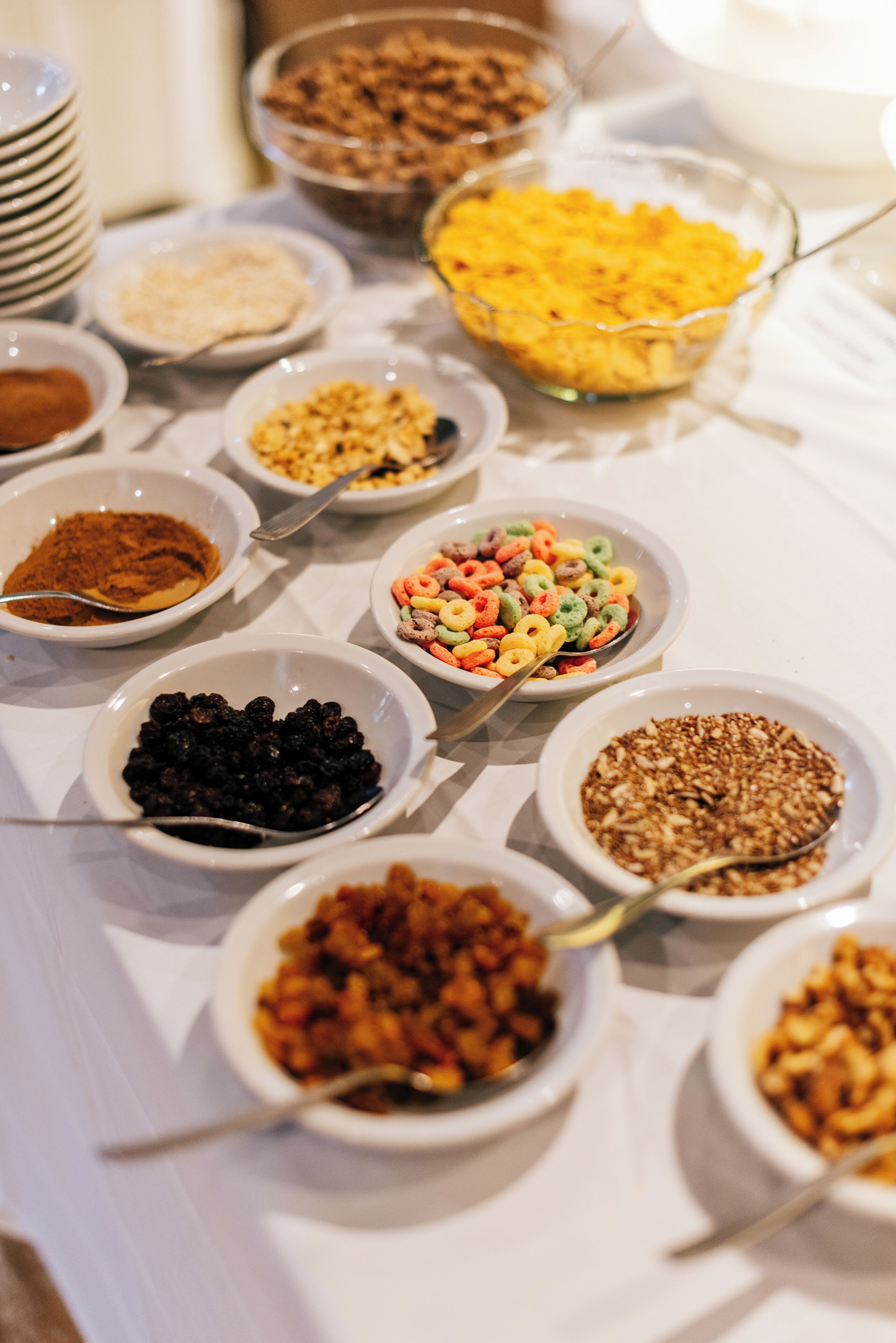 A table with various bowls of food, including cereals, nuts, and dried fruits.