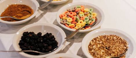 A table with various bowls of food, including cereals, nuts, and dried fruits.