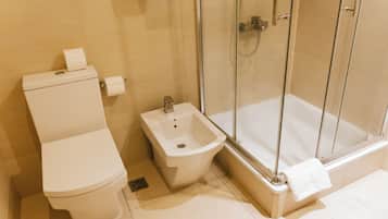 A bathroom with a toilet, bidet, and glass-enclosed shower.