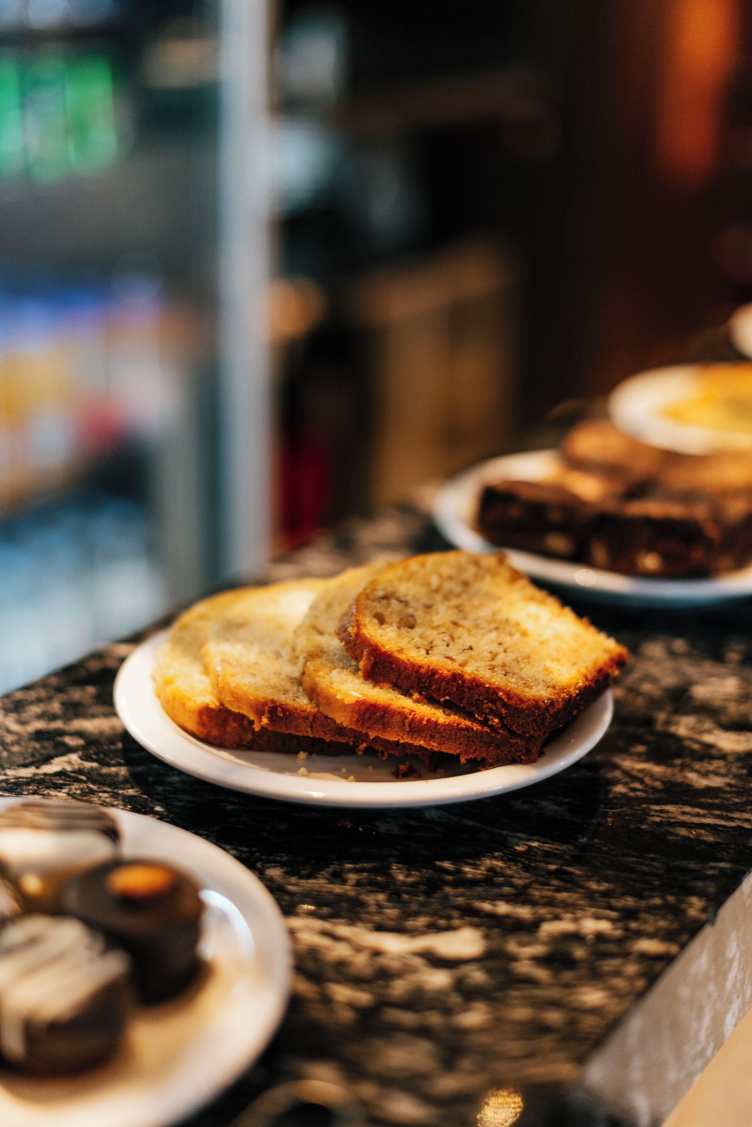 A countertop with plates of food, including bread and pastries.