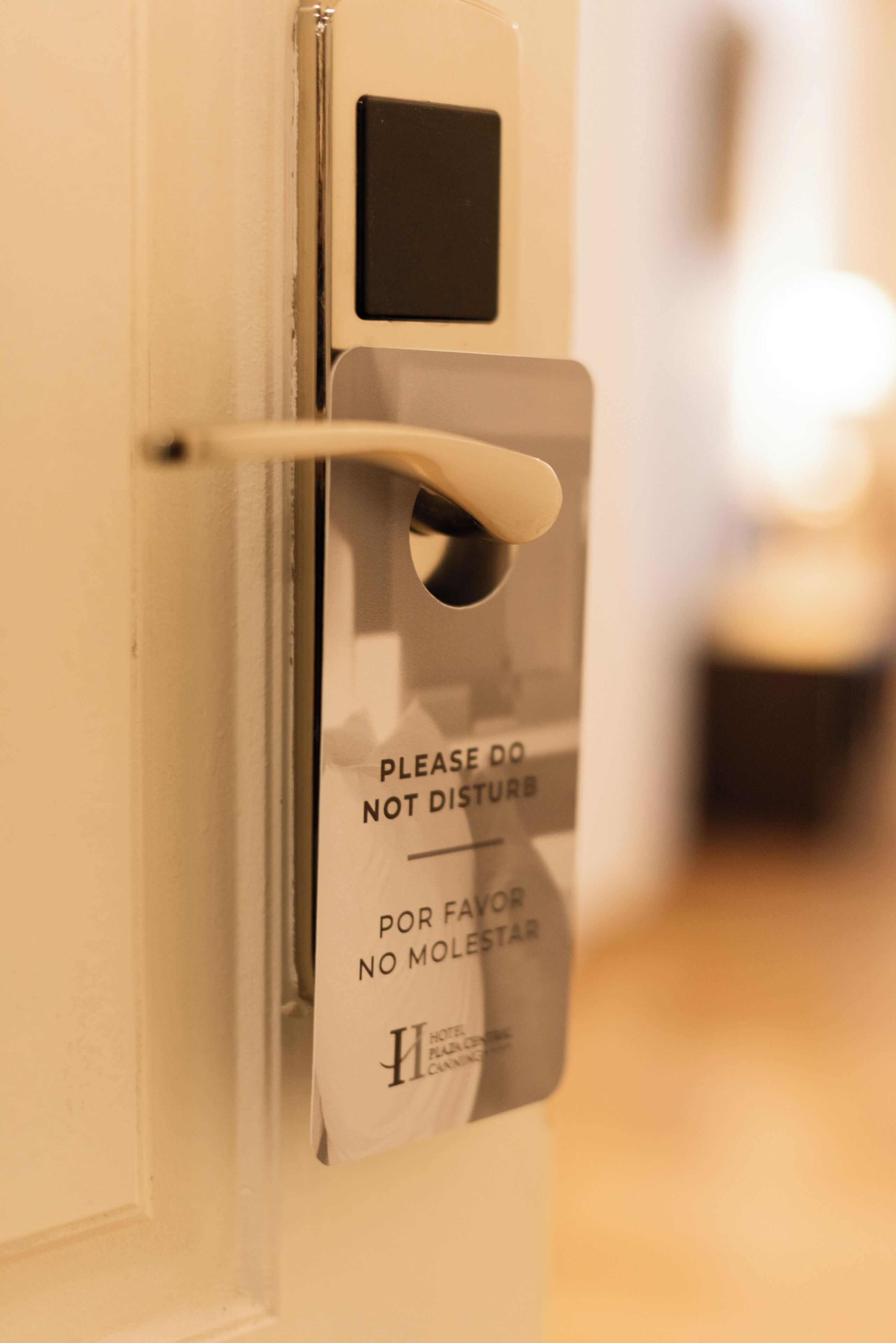 A hotel door with a sign that reads "PLEASE DO NOT DISTURB" and "POR FAVOR NO MOLESTAR".