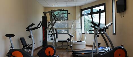 Un gimnasio con bicicletas estáticas, cintas de correr y una máquina de pesas.