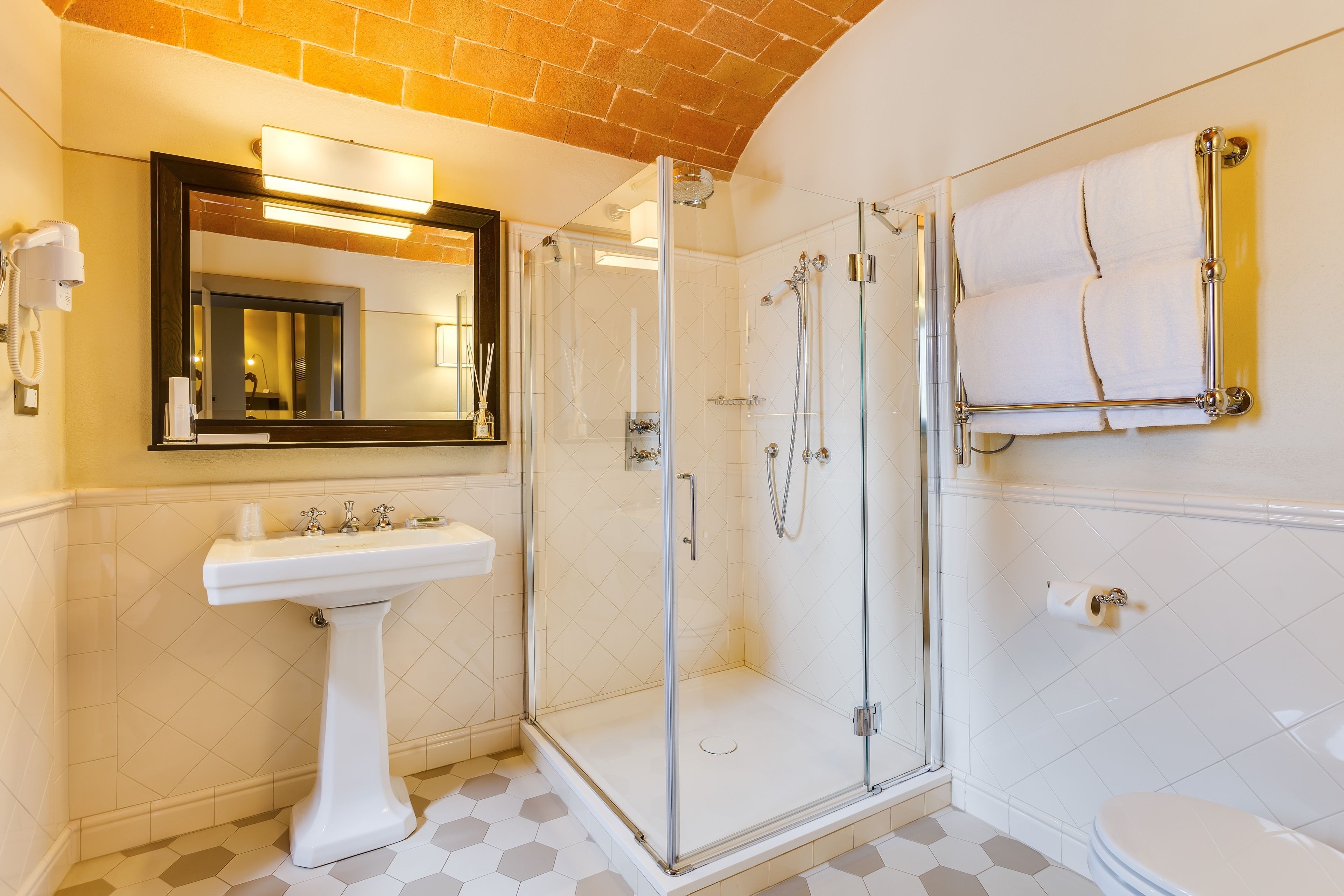 Un bany modern amb dutxa de vidre, un lavabo pedestal i un vàter.