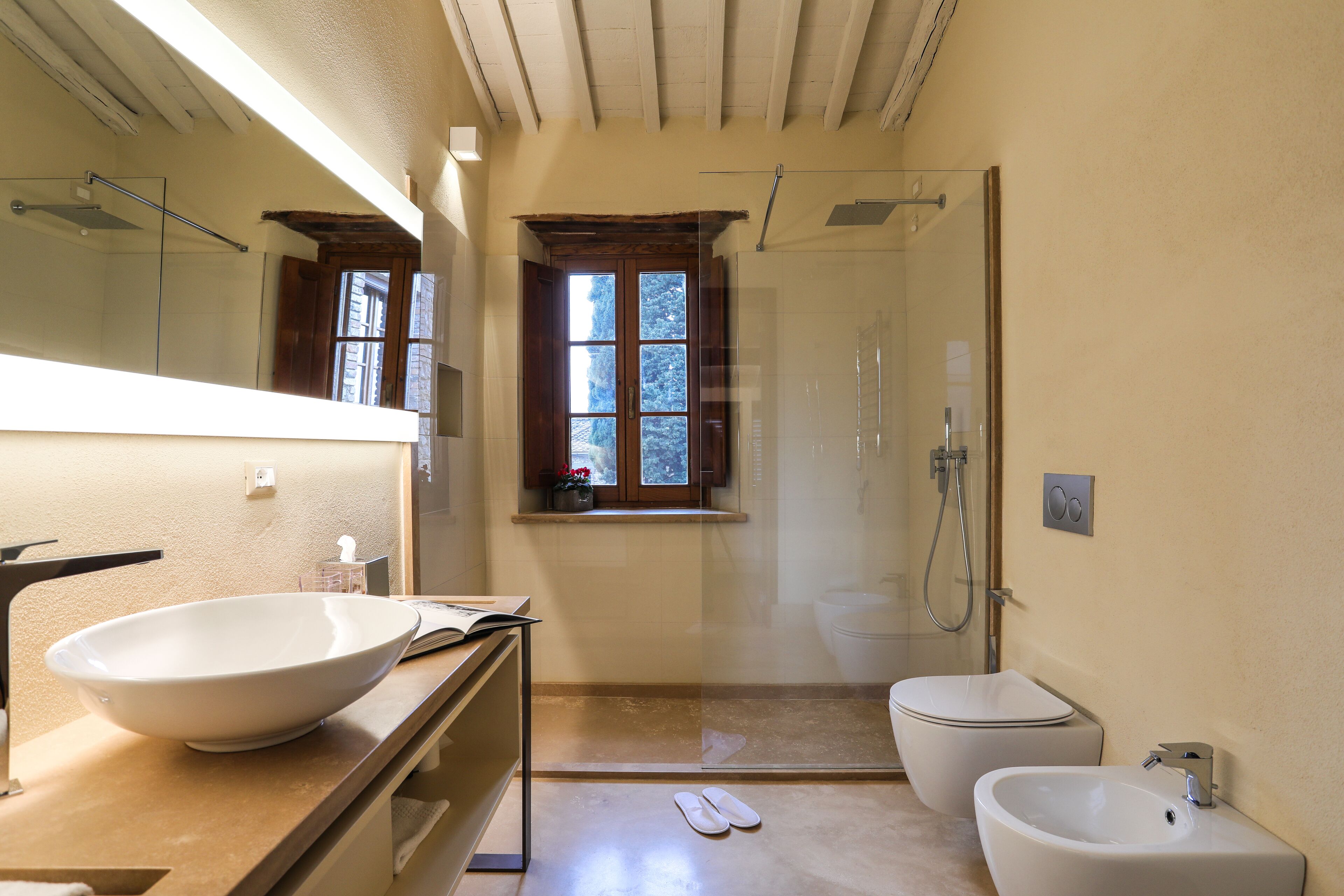 Un baño con un lavamanos grande blanco, un bidé, un inodoro y una cabina de ducha de vidrio.