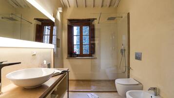 Un baño con un lavamanos grande blanco, un bidé, un inodoro y una cabina de ducha de vidrio.