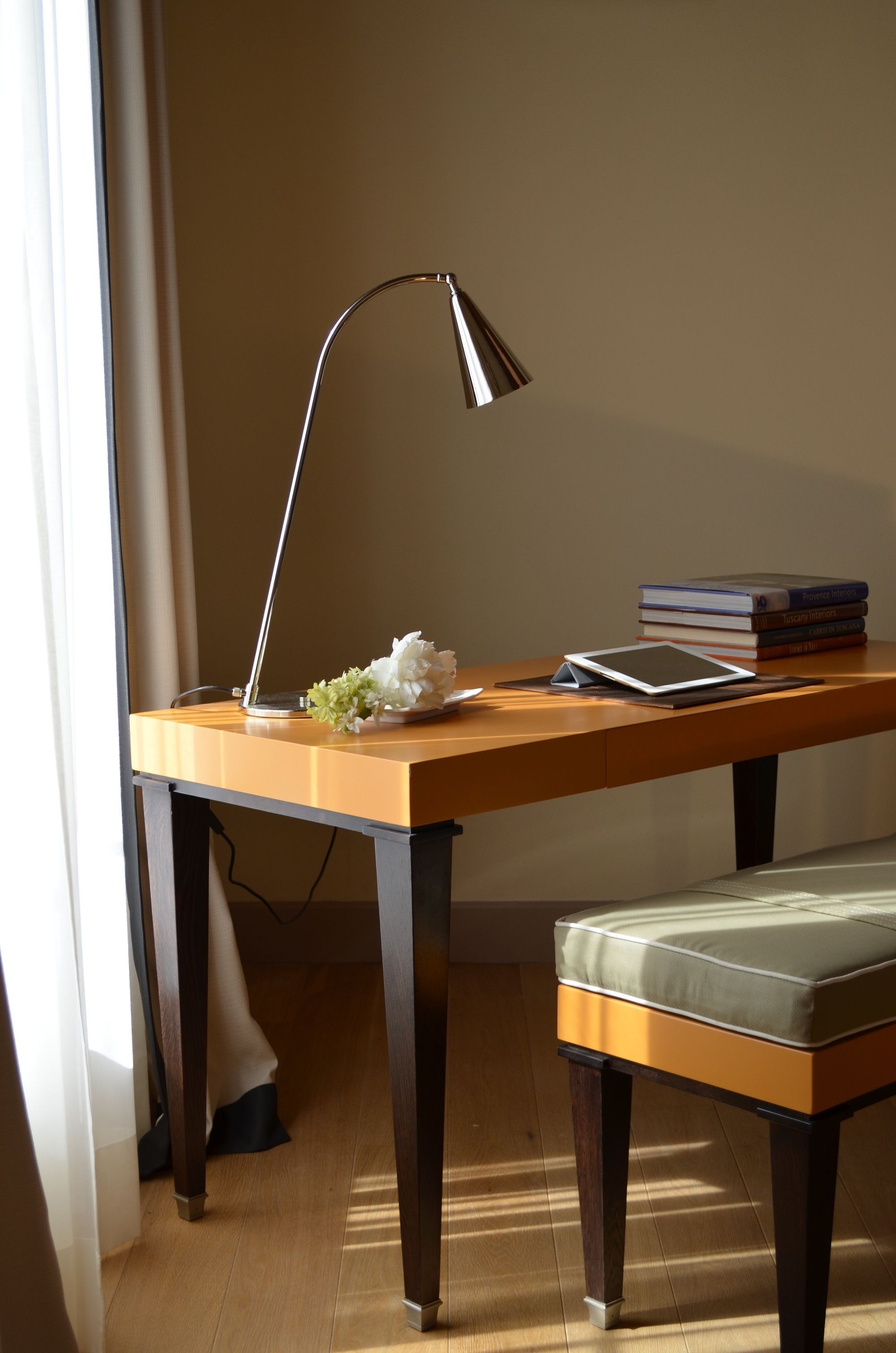 Escritorio de madera con una lámpara, una tableta y libros.
