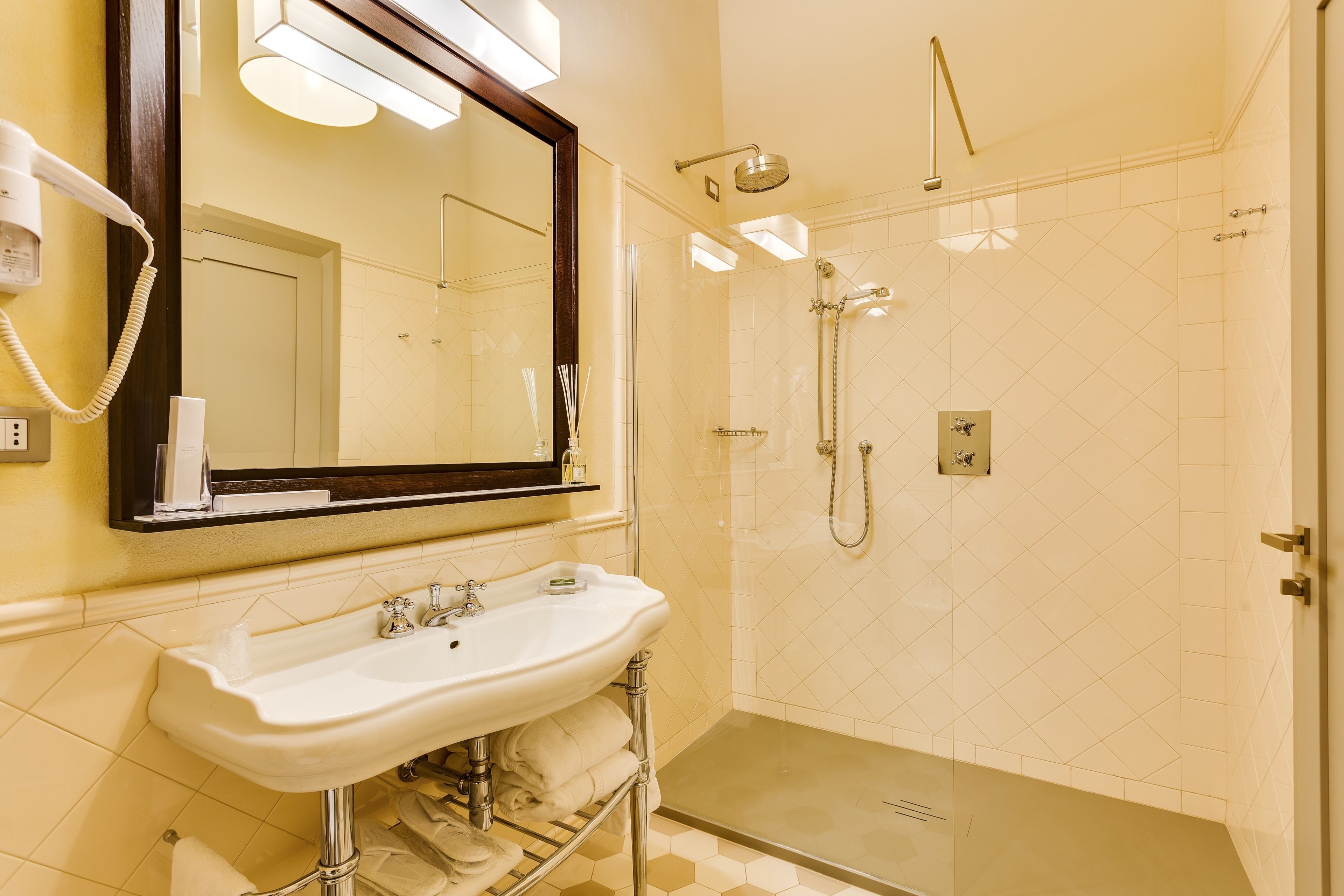 A modern bathroom with a large mirror, a sink, and a glass-enclosed shower area.