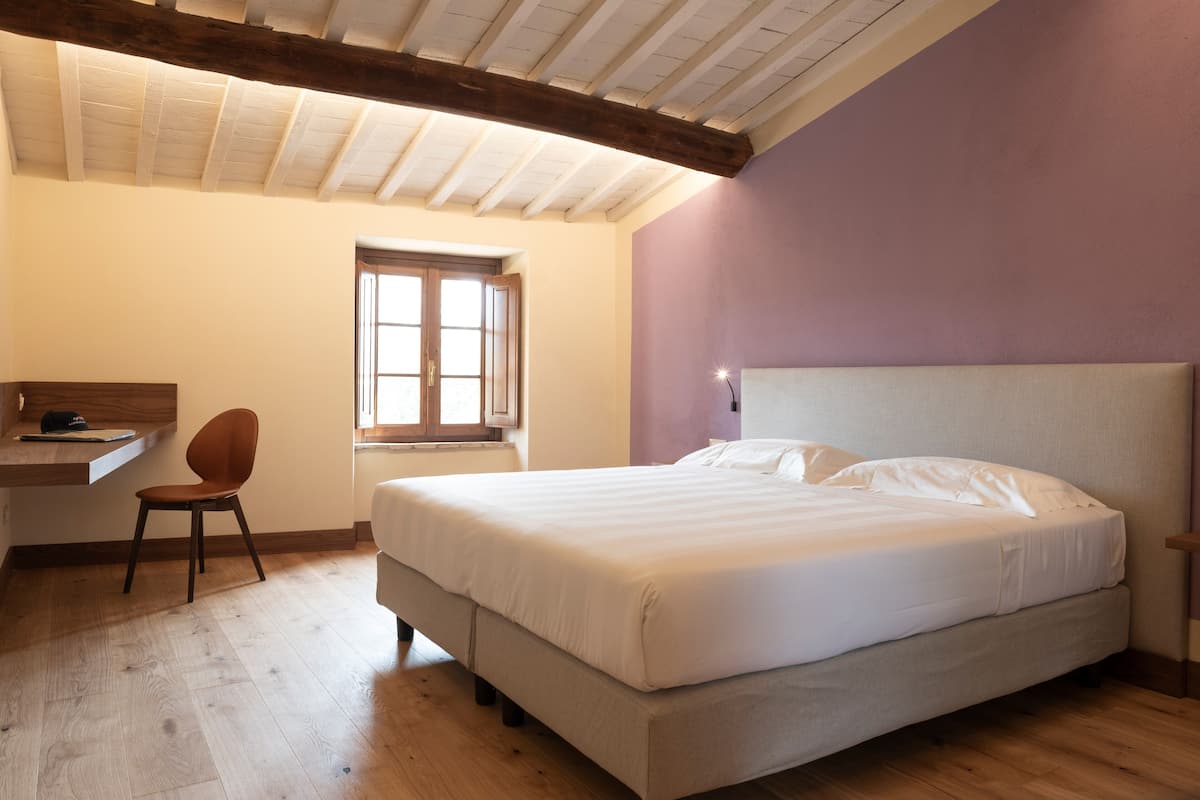 A bedroom with a bed, a desk, and a chair.