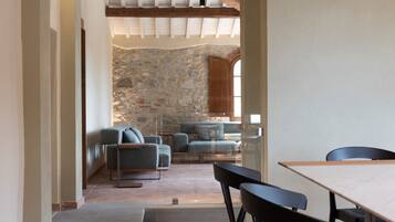 A modern interior with a stone wall, a wooden ceiling, and a dining area with a table and chairs.