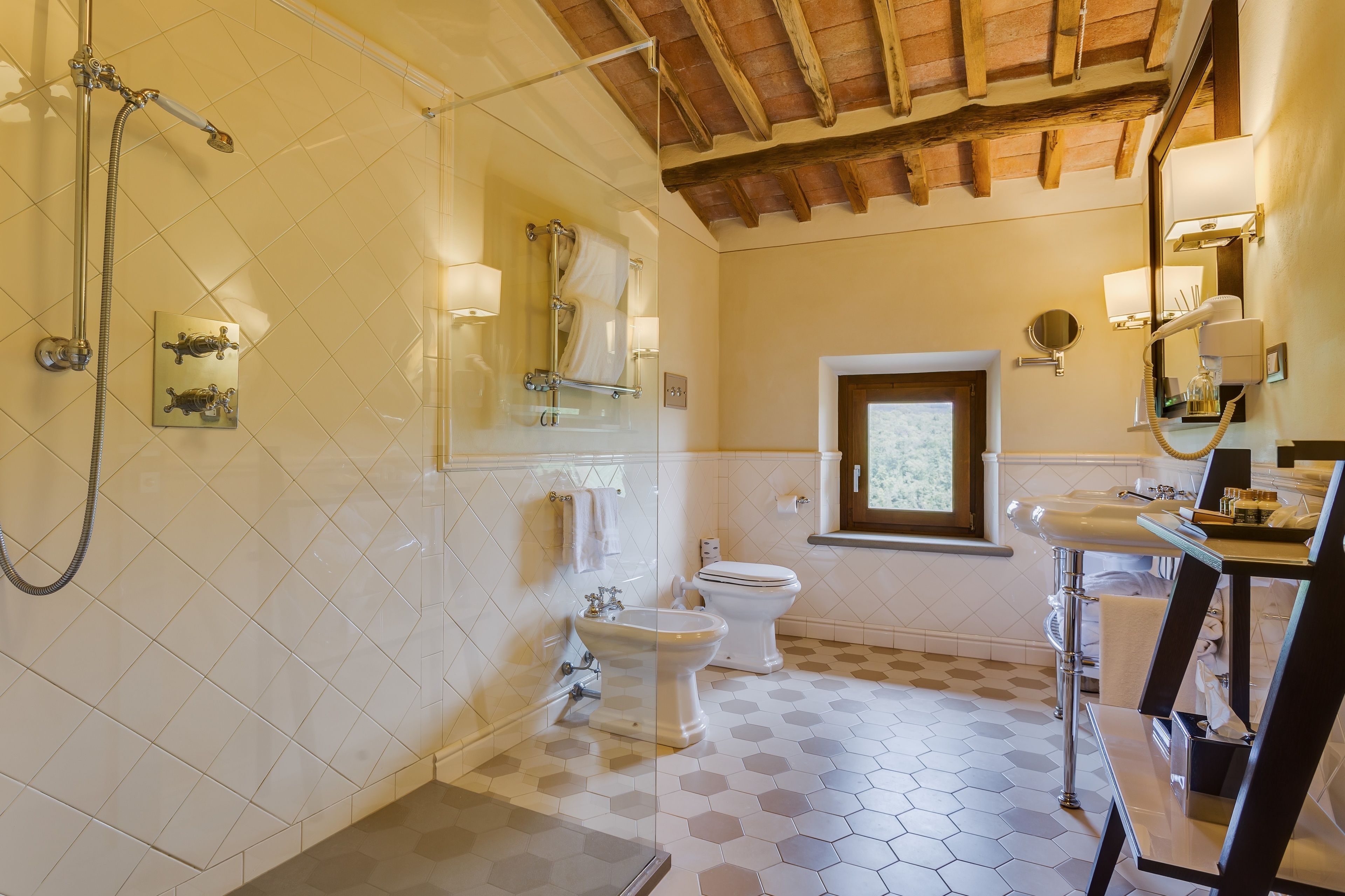 Ein Badezimmer mit Dusche, Toilette und Waschbecken, mit sechseckisch gemusterten Fliesen und Holzbalken an der Decke.