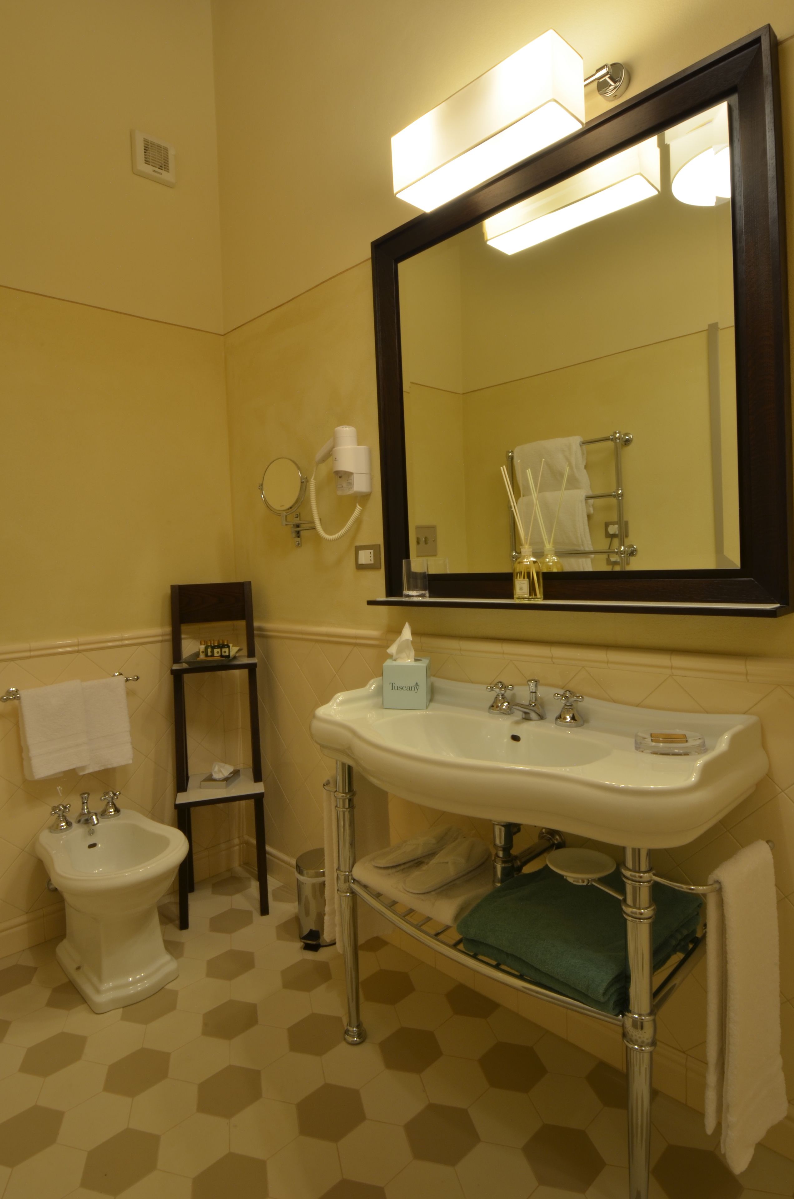 Une salle de bain avec un lavabo blanc, un miroir, un bidet et un porte-serviettes.