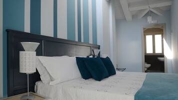 Ein Schlafzimmer mit einem Bett, einem Nachttisch, einer Lampe und einem Fenster.