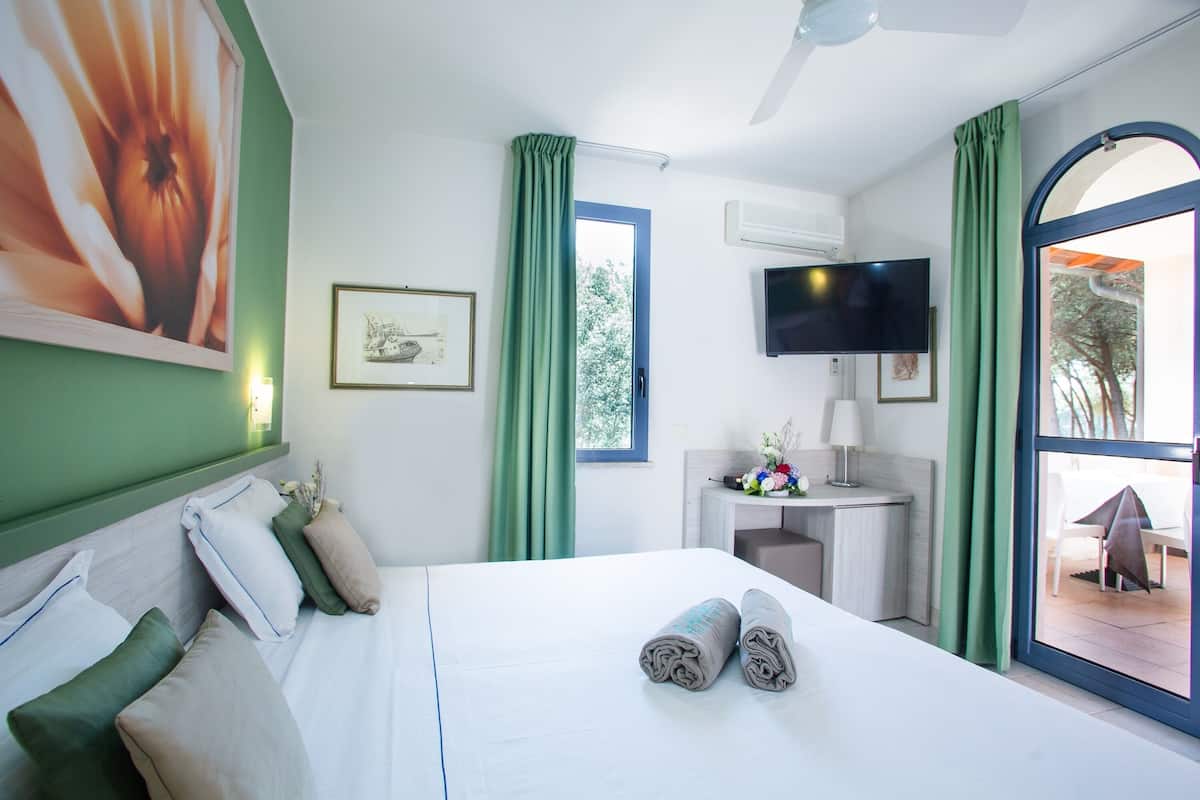 Ein Hotelzimmer mit Bett, Schreibtisch, Fernseher und Blick ins Freie.