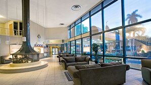 A spacious lobby with a large fireplace, comfortable seating, and large windows offering views of the outside.
