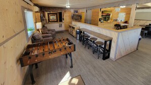 Un espacio interior acogedor con mesa de fútbol, barra y asientos.
