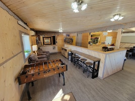 A cozy indoor space with a foosball table, bar area, and seating.