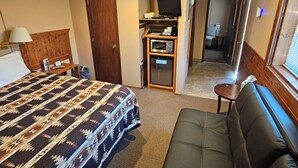 Una habitación de hotel con cama, sofá, televisor y microondas.