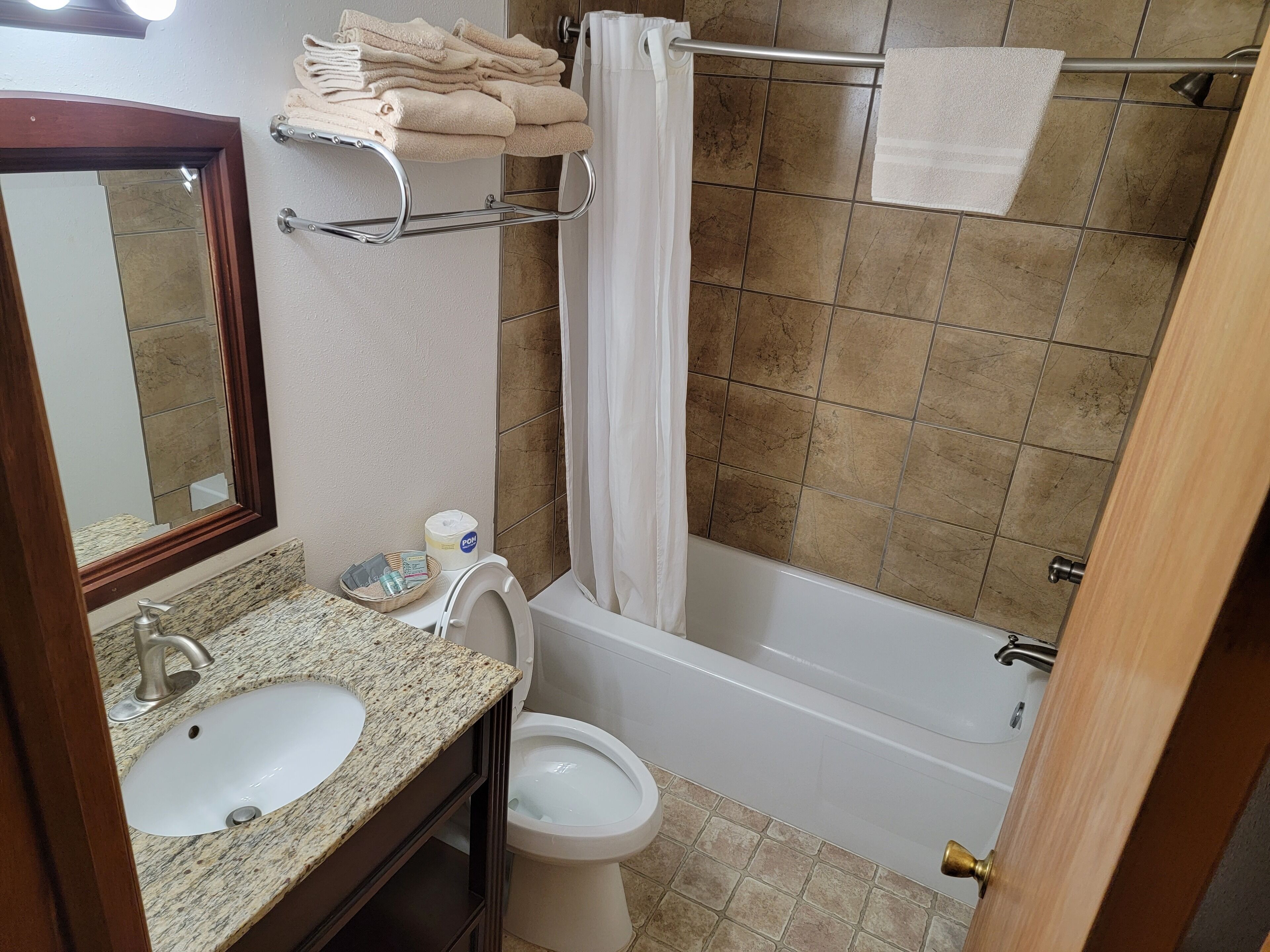A bathroom with a sink, toilet, and bathtub. There are towels on a rack and a shower curtain.