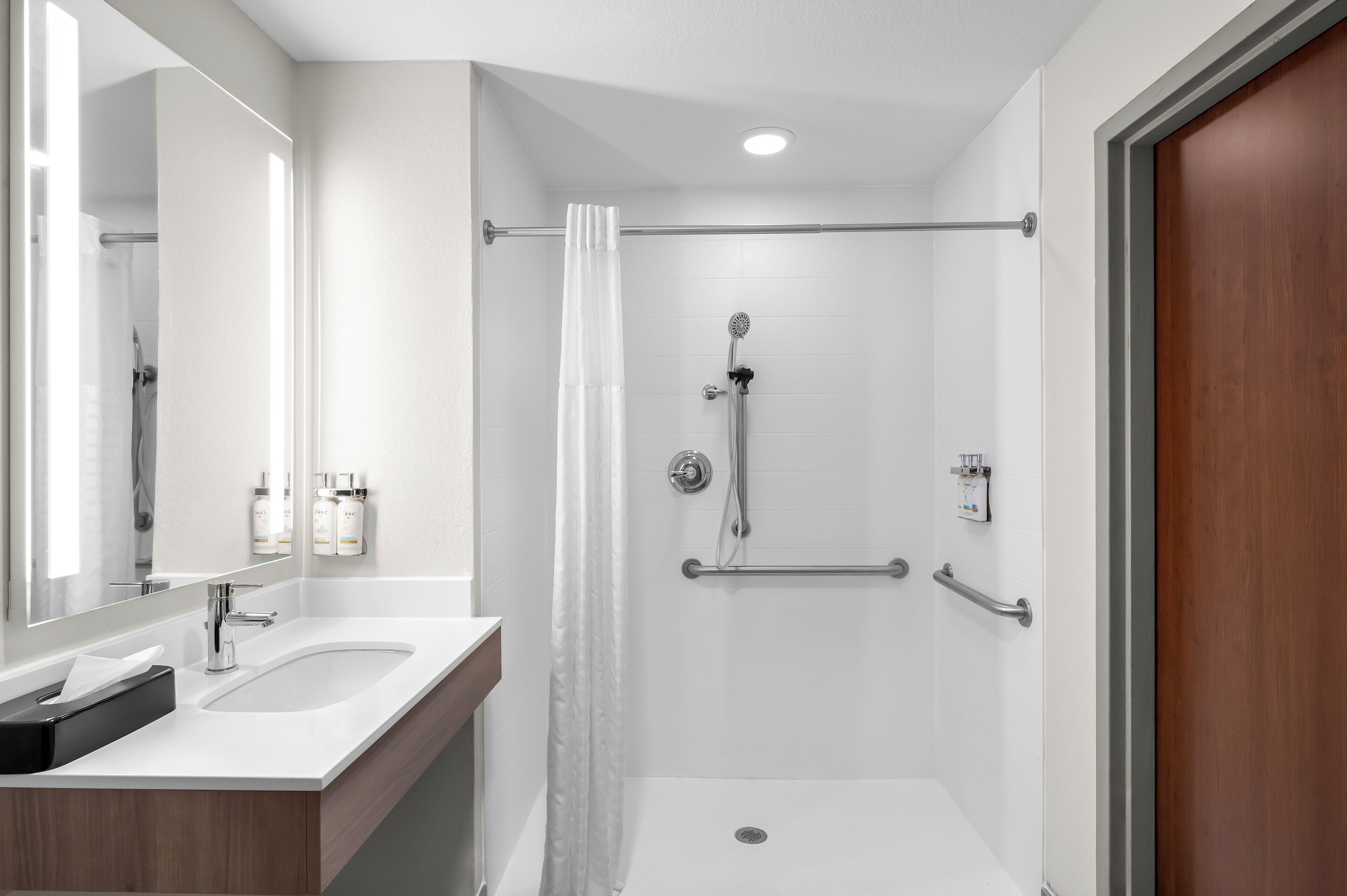 Een moderne badkamer met een douche, wastafel en spiegel.