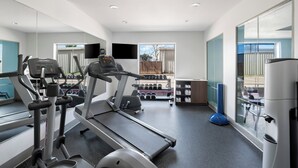 Une salle de sport moderne équipée de tapis de course, d’haltères et d’un ballon d’exercice bleu.