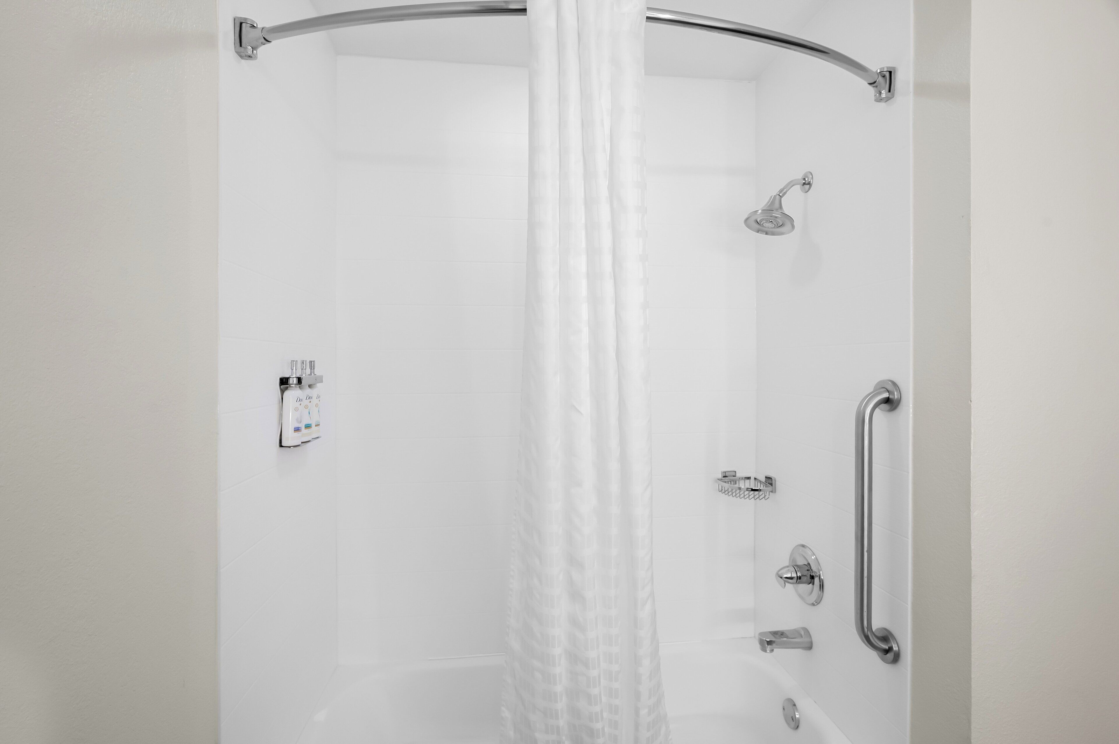 Eine moderne Dusche mit Glasabtrennung, Handbrause und Auszugshahn, sowie einer Haltestange.
