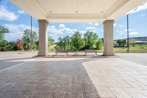 A covered outdoor area with stone flooring, benches, and a view of a road and greenery. - Holiday Inn Express & Suites Morrilton by IHG (Morrilton)