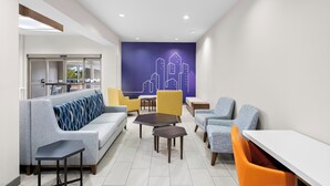 A modern lounge area with a sofa, chairs, tables, and a cityscape mural on the wall. - Holiday Inn Express & Suites Morrilton by IHG (Morrilton)