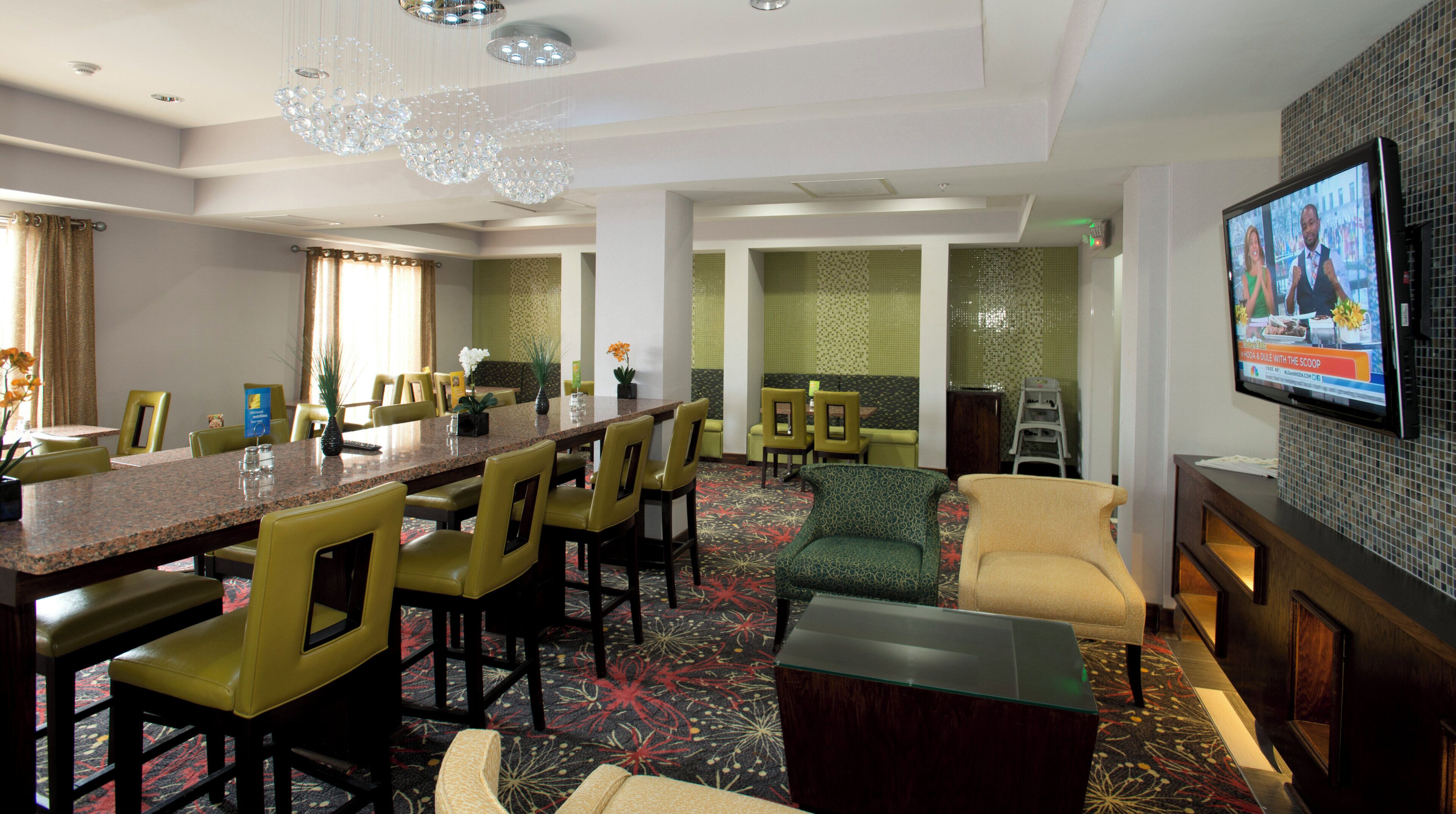 Una habitación de hotel con zona de comedor, sofá, televisor y chimenea.