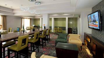 Una habitación de hotel con zona de comedor, sofá, televisor y chimenea.