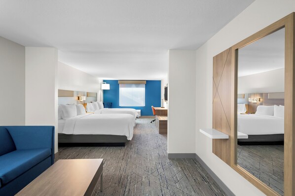 A hotel room with a large bed, a smaller bed, a desk, a chair, a blue sofa, and a large mirror. - Holiday Inn Express & Suites Morrilton by IHG (Morrilton)
